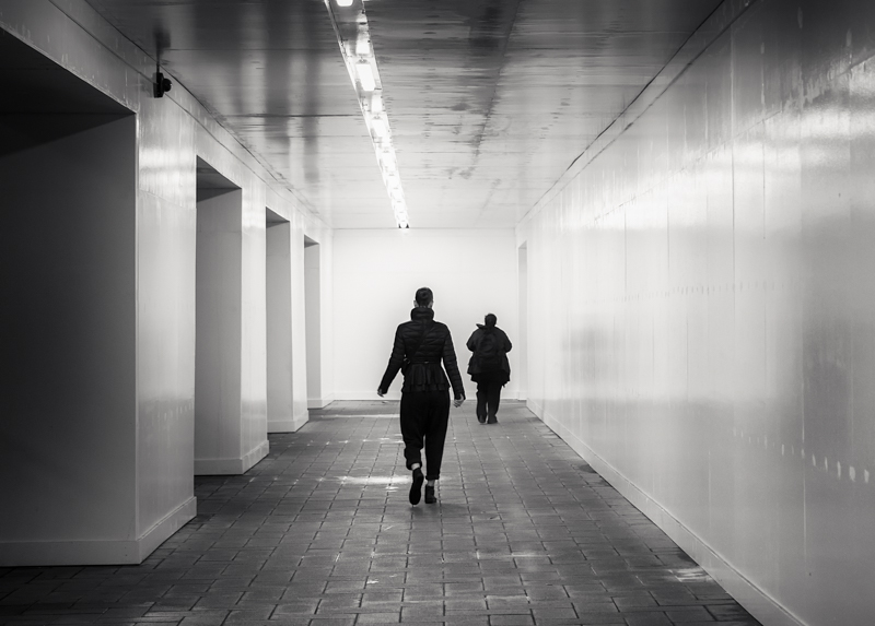Distanced figures in an urban pathway by Jukka Heinovirta